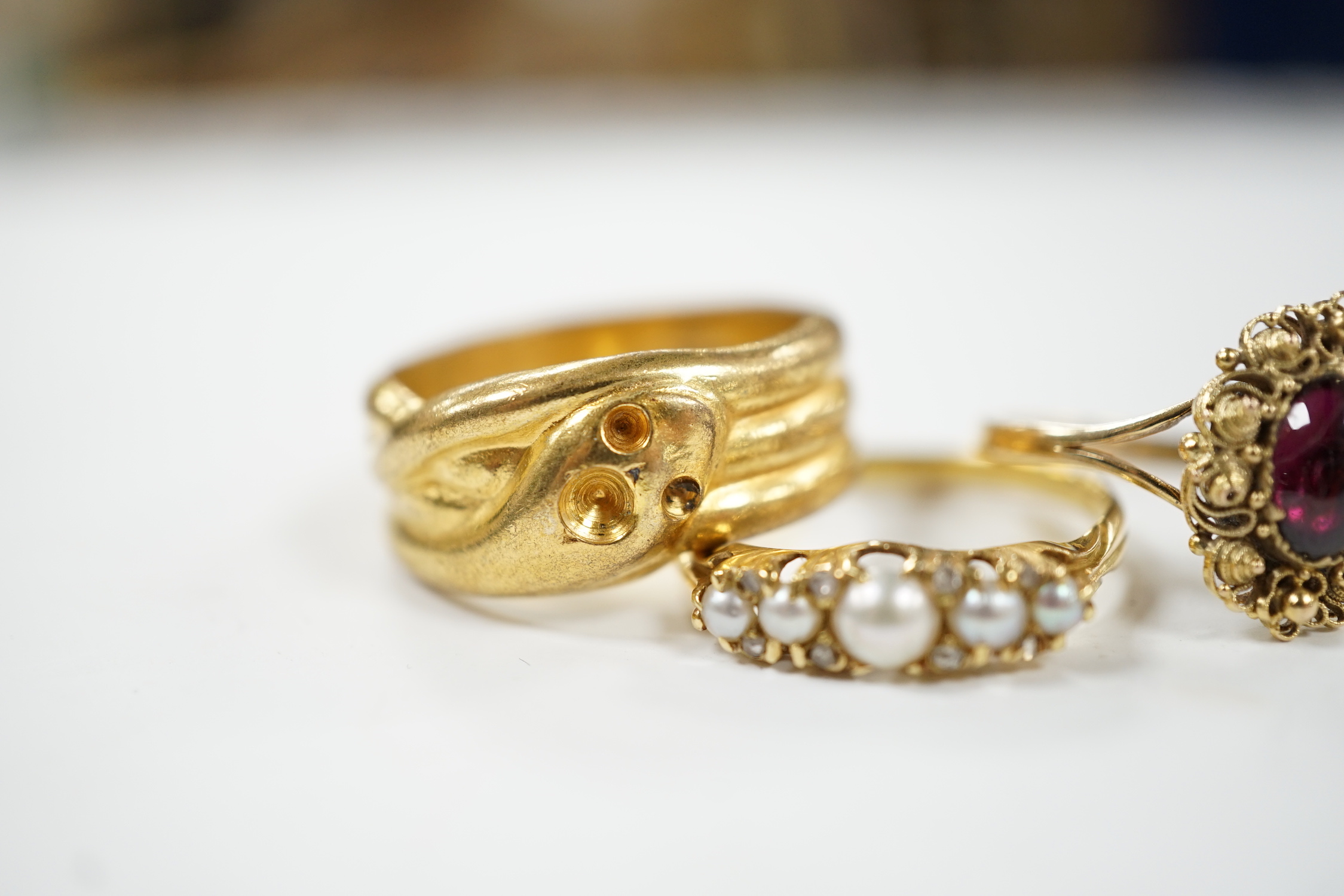 A yellow metal and cabochon garnet set ring, an Edwardian 18ct and graduated split pearl set half hoop ring, with diamond chip spacers and one other ring.